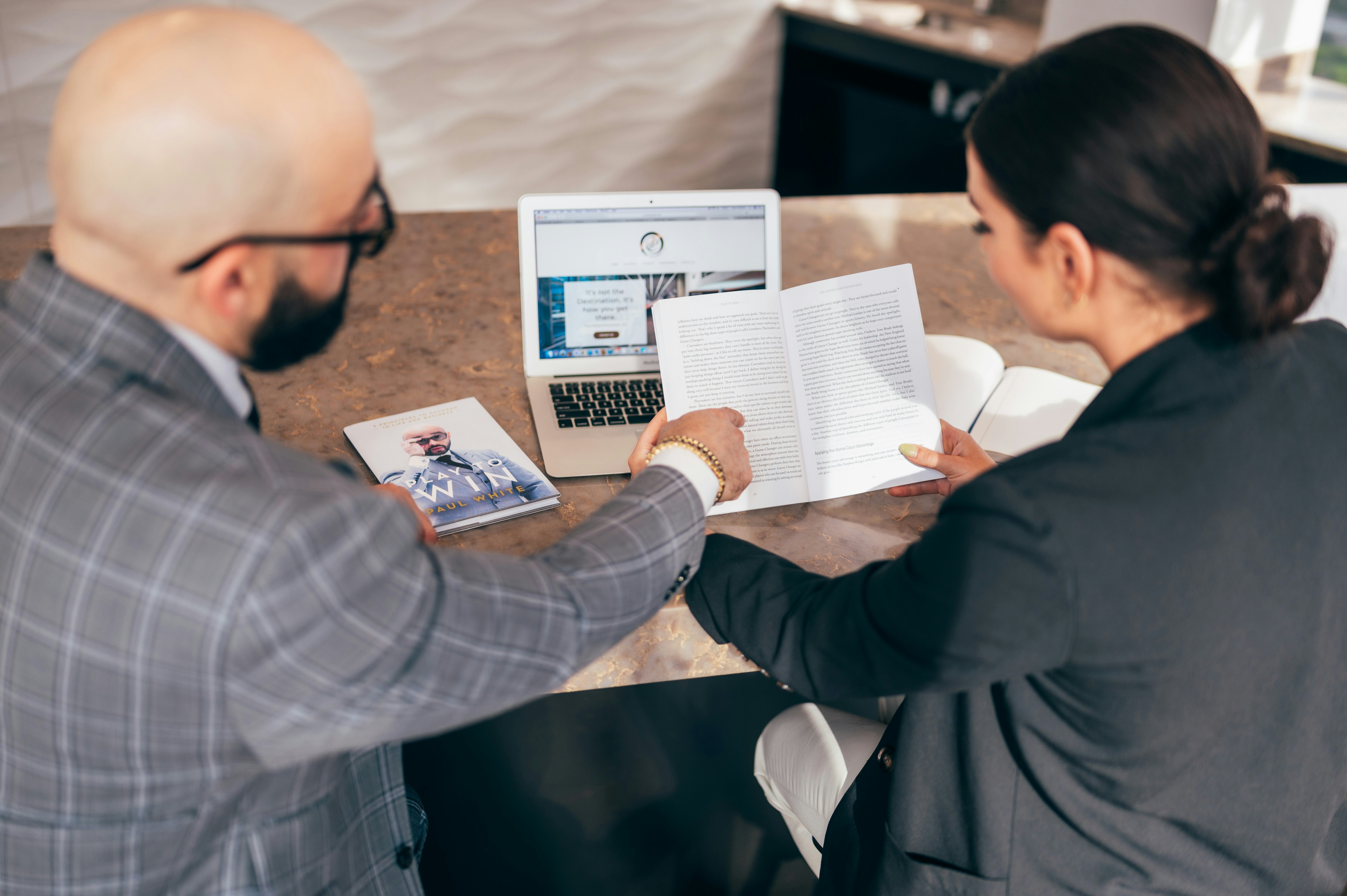 Two people reviewing a website on a laptop alongside printed materials