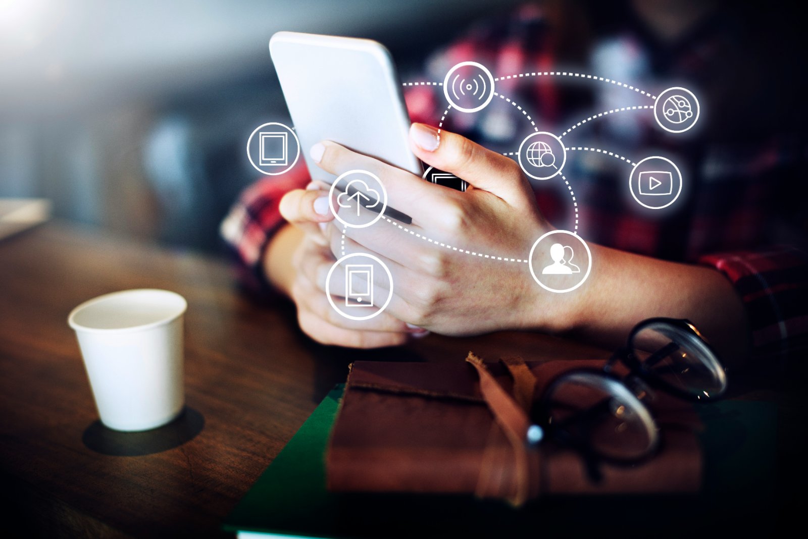 Person holding a phone with connected service icons floating around it