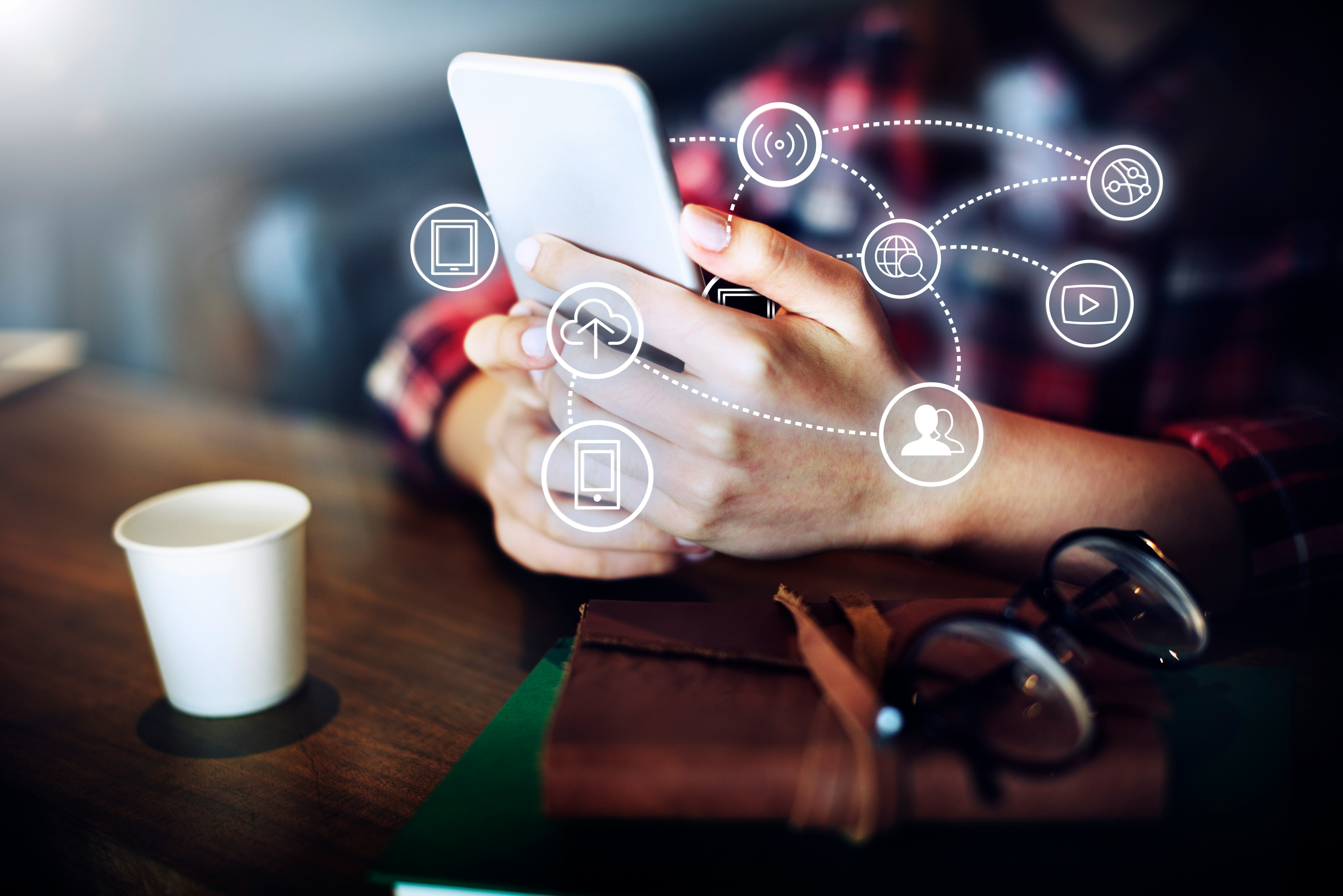 Person holding a phone with connected service icons floating around it