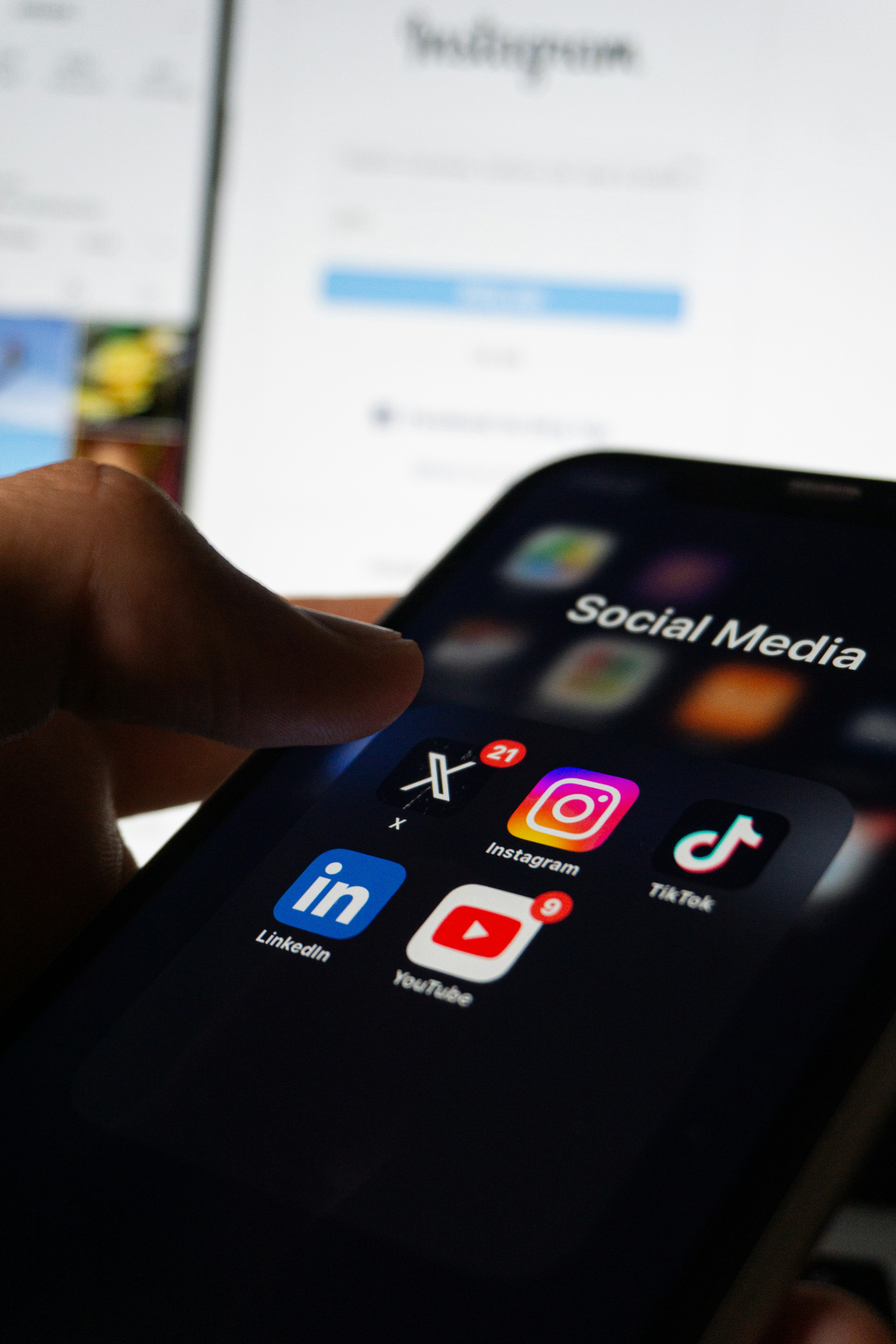 Phone showing social media apps including Instagram, TikTok, X, LinkedIn, and YouTube